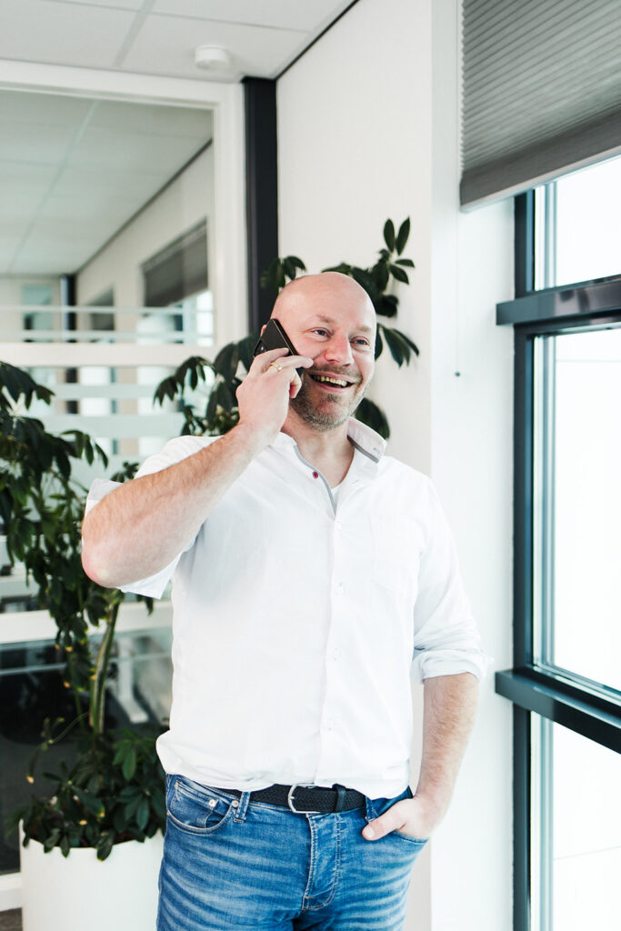 Een man staat lachend te bellen.